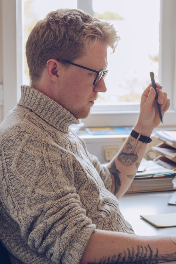 Lasse Petersdotter im Büro am Schreibtisch nachdenklich